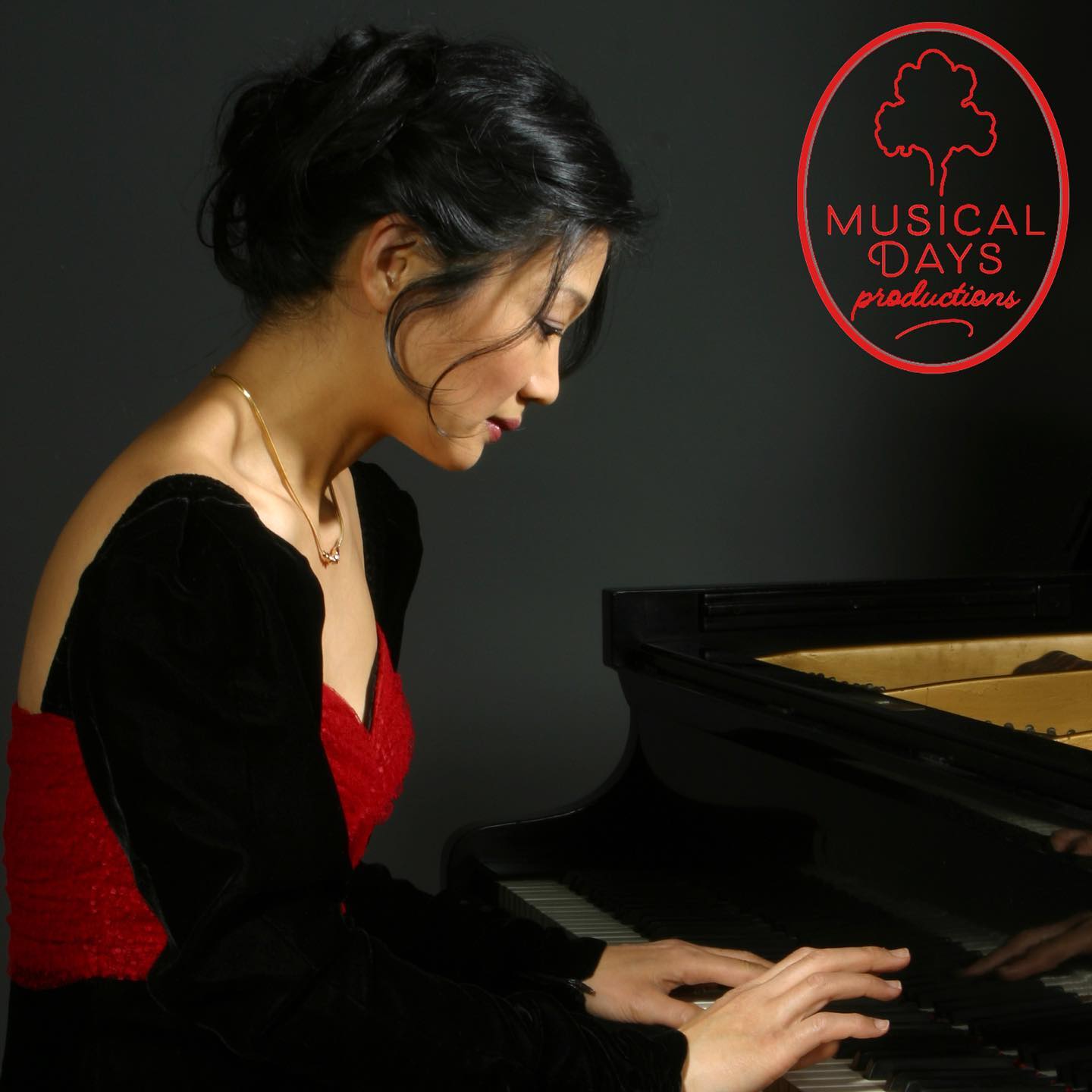 Photo of Asian woman in black dress sitting and playing at a piano