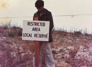 Vietnamese man standing in front of a white sign that says Restricted Area, Local Reserve